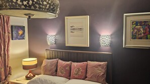 A bedroom with a bed, a nightstand, a lamp, and wall-mounted sconces. - Lovely 3 bedroom bungalow in Keswick with gardens and ample off road parking (Keswick)