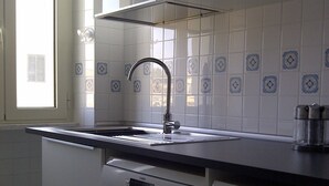 A kitchen with white cabinets, a Bosch dishwasher, a Bosch washing machine, a stainless steel sink, and decorative blue and white tiles on the wall. - ROMAN HOLIDAYS, TWO STEPS FROM SAN PIETRO FULL OPTIONALS (Roma)