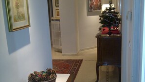 A hallway with a wooden bench, a potted plant, a Christmas tree, and framed artwork on the walls. - ROMAN HOLIDAYS, TWO STEPS FROM SAN PIETRO FULL OPTIONALS (Roma)