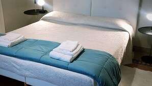 A neatly made bed with a blue and white duvet, a white pillow, and folded towels on the bed. There are two bedside tables with lamps, one on each side of the bed. - ROMAN HOLIDAYS, TWO STEPS FROM SAN PIETRO FULL OPTIONALS (Roma)