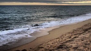 A beach with waves approaching the shore under a cloudy sky. - In Cabrils (Barcelona at 20 km). Apartment with sea view, pool and very quiet (Cabrils)