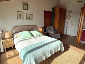 Une chambre à coucher comprenant un lit, des tables de chevet, une chaise et une armoire.