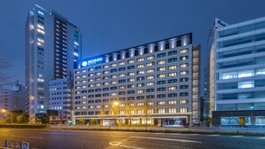 Un moderno edificio de hotel con varios pisos, ventanas iluminadas y un cartel llamativo.