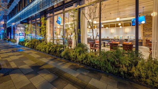 Un restaurante moderno con terraza, ventanas amplias y un interior bien iluminado.