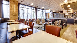 Un restaurante moderno con techo de madera, ventanas amplias y diferentes opciones de asientos, como cabinas y mesas.