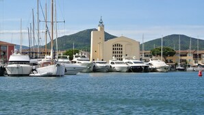 A marina with several yachts docked, a church with a bell tower, and a mountainous backdrop. - APP 3 rooms, private residence 25hect, 4 pers, private garden, sea view,  (Grimaud)