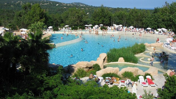 A large outdoor swimming pool surrounded by lush greenery, with multiple levels and a rocky landscape. - APP 3 rooms, private residence 25hect, 4 pers, private garden, sea view,  (Grimaud)
