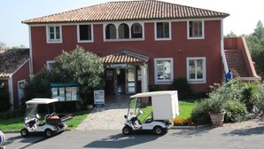 A red building with a tiled roof, a reception area, and two golf carts parked in front. - APP 3 rooms, private residence 25hect, 4 pers, private garden, sea view,  (Grimaud)