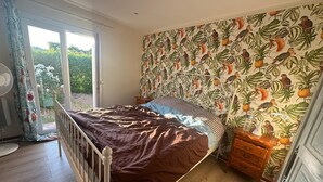 A bedroom with a bed, a wooden dresser, a nightstand, and a window with curtains. - Sainte Maxime: House with garden on french riviera. Terrace with solarium (Sainte-Maxime)