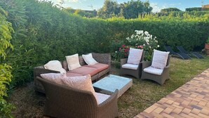 An outdoor seating area with wicker furniture and a glass table, surrounded by a hedge and flowers. - Sainte Maxime: House with garden on french riviera. Terrace with solarium (Sainte-Maxime)