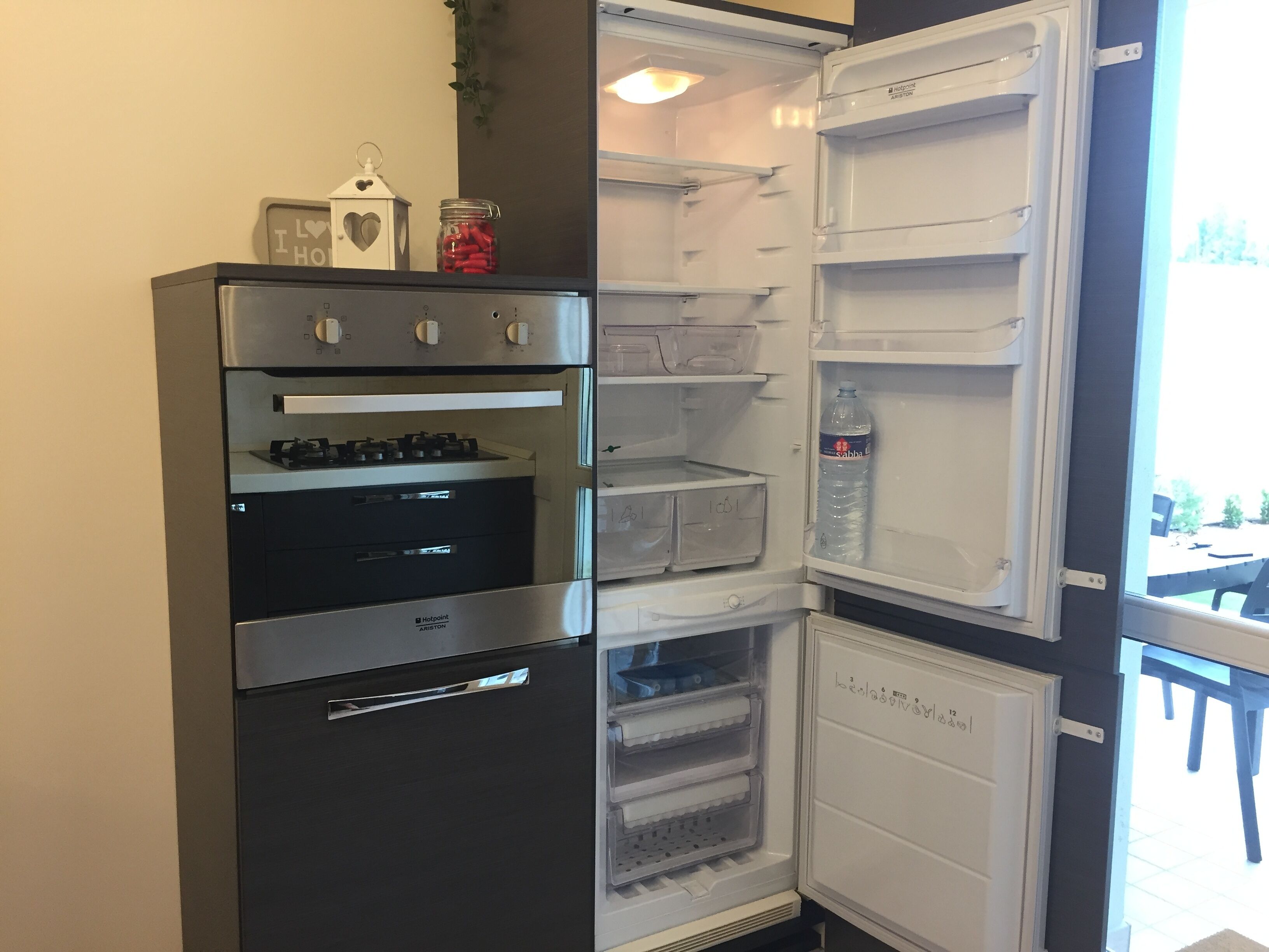 Una cocina compacta con horno empotrado y un refrigerador con dispensador de agua.