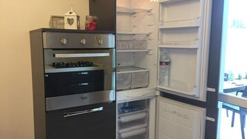 Una cocina compacta con horno empotrado y un refrigerador con dispensador de agua.
