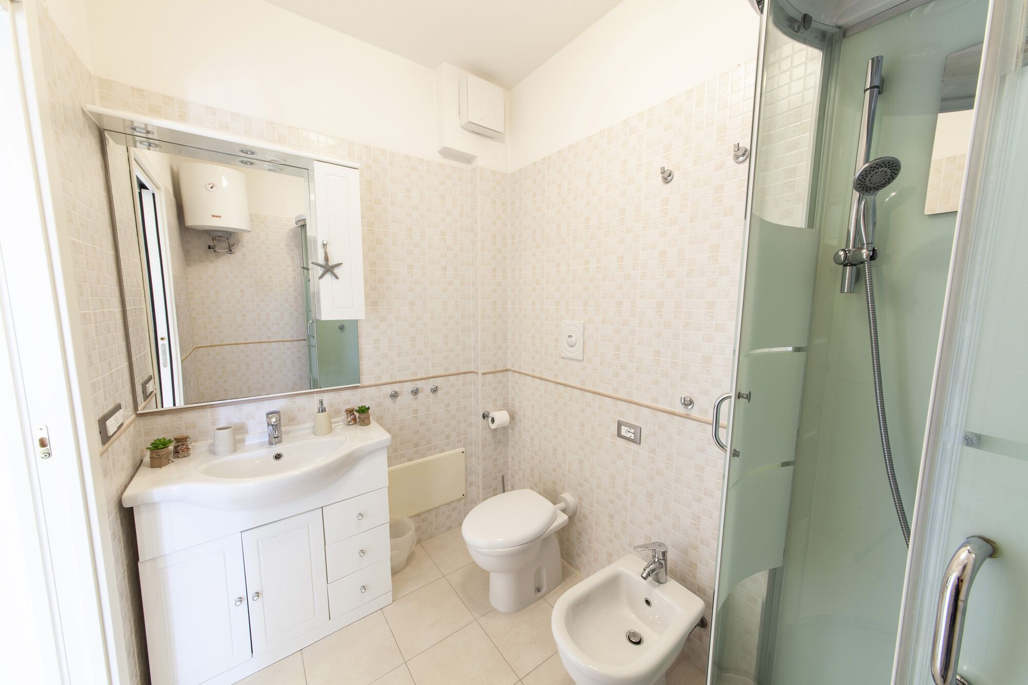Un bagno moderno con doccia vetrata, lavandino bianco, WC e bidet.