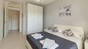 Une chambre à coucher avec un lit, des rideaux blancs, un lustre et une œuvre d’art murale.