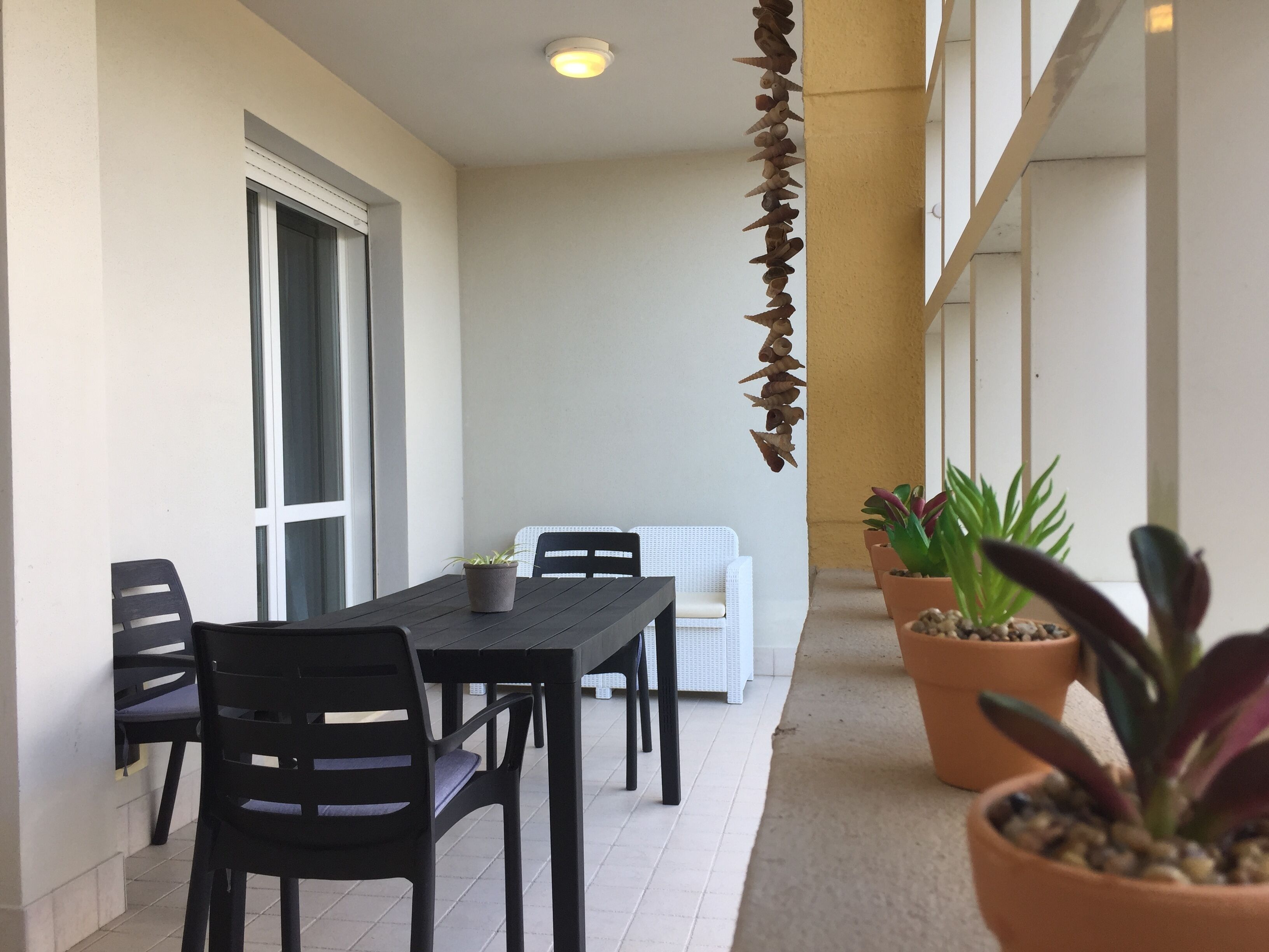 A patio area with a table and chairs, potted plants, and a white sofa.