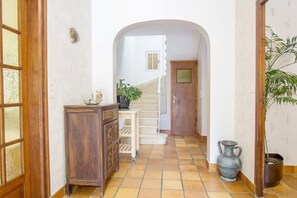 Ein Flur mit einem Holzkasten, einem kleinen Tisch mit einer Pflanze, einer Treppe und einem Blumentopf.