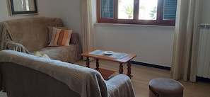 Uma sala de estar acolhedora, com um sofá, poltrona e uma pequena mesa de madeira.