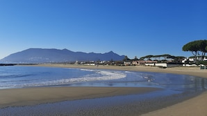 A beach with a mountain in the background, clear skies, and a calm sea.