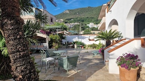 A courtyard with outdoor furniture, potted plants, and a staircase leading to an upper level.