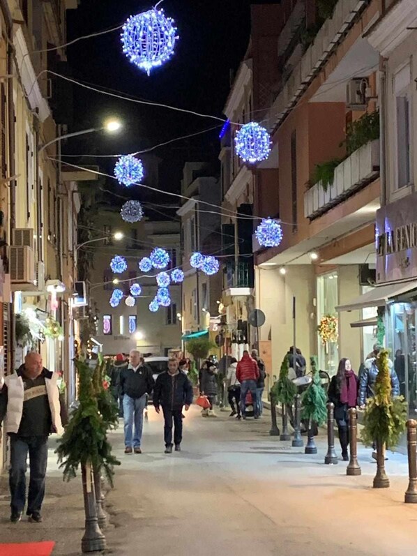 Une rue bordée de boutiques et illuminée de guirlandes lumineuses bleues en forme de sphères.