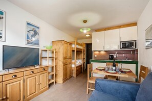 A compact living space with a kitchenette, a dining area, and a television. - Cham Sud F210 Mountain View for 4, Chamonix, France (Chamonix)