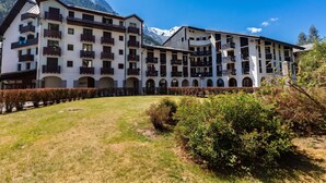 A multi-story hotel with balconies, arched walkways, and a mountainous backdrop. - Cham Sud F210 Mountain View for 4, Chamonix, France (Chamonix)
