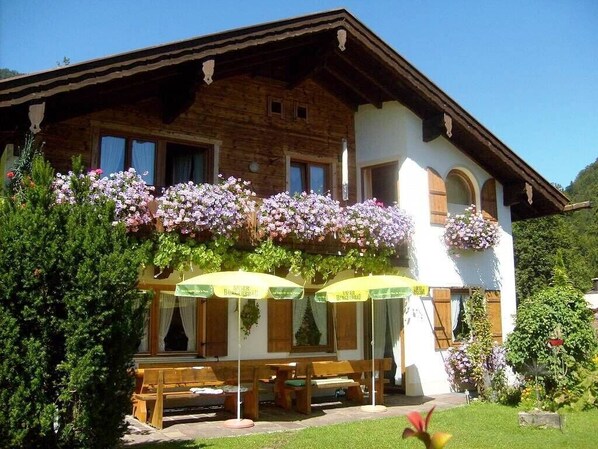 Un chalet en bois doté d’un balcon, d’un espace salon extérieur et de jardinières suspendues.