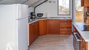 A compact kitchen with wooden cabinets, a microwave, a coffee maker, and a window providing natural light. - Nice home in Give with WiFi (Give)