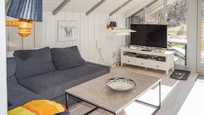 A modern living room with a grey sofa, a coffee table, and a TV on a white cabinet. - Nice home in Give with WiFi (Give)