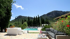 A poolside area with a white sofa, a wicker table, and a stone floor. - Finca Ramona, Pool, 6 bedrooms , A / C, Wi-Fi, smart TV (Pollença)