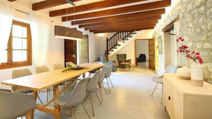 A spacious dining area with a long wooden table, several chairs, and a staircase leading to another room. - Finca Ramona, Pool, 6 bedrooms , A / C, Wi-Fi, smart TV (Pollença)