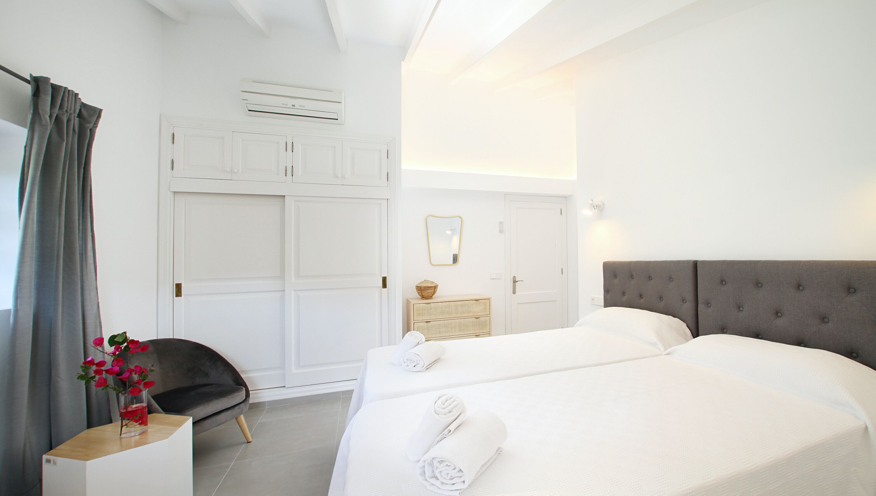 A hotel room with two beds, a wardrobe, a vanity, and a chair.