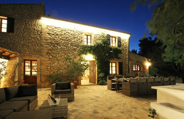 A stone building with outdoor seating and a well-lit entrance.
