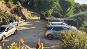 A parking area with several cars and a covered structure.