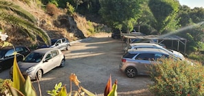 A parking area with several cars and a covered structure.