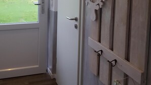 A hallway with a white door, a wooden wall with a 'HOME' sign, and a 'Willkommen' sign.