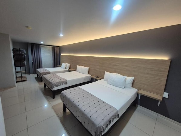 Habitación de hotel con tres camas, un escritorio y una silla.