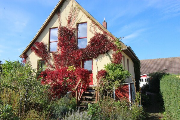 A house with a steeply pitched roof, a visible chimney, and a front door with a small porch. - Organic vacation home, 3sleepR, 2 BathR, natural garden, sauna, WLAN, dogs allow (Altenkirchen)