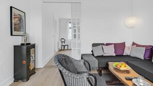 A modern living room with a sofa, a dining table with fruit, and a vintage radio. - 1 bedroom cozy apartment in Svendborg (Svendborg)