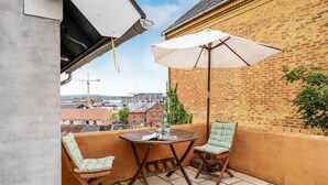 A small balcony with two chairs and a table, a white umbrella, and a view of the cityscape. - 1 bedroom cozy apartment in Svendborg (Svendborg)
