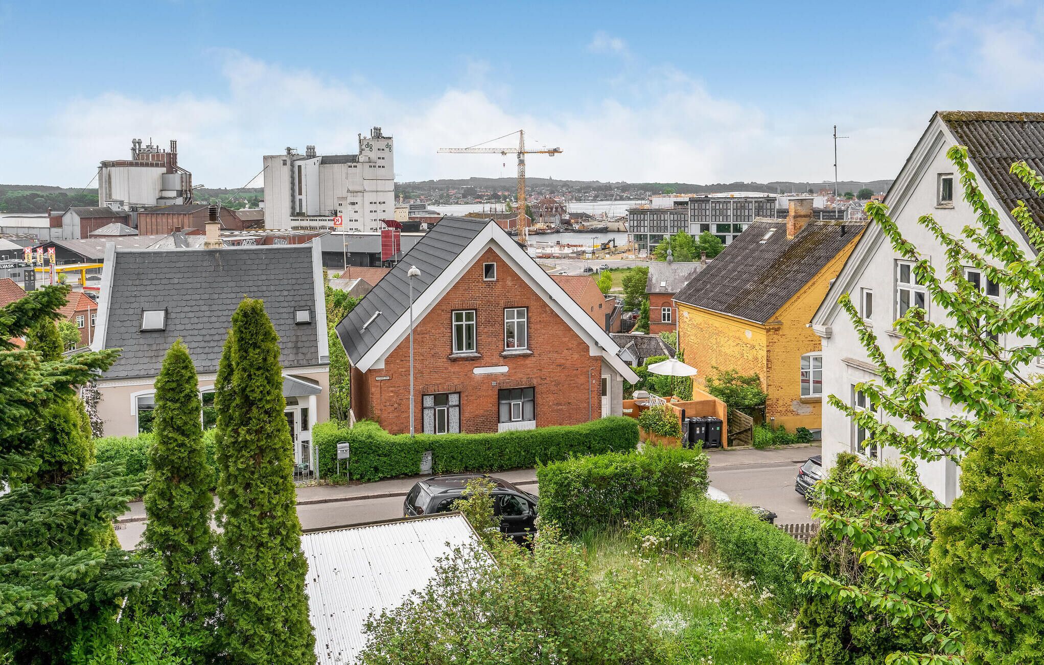 A residential area with houses, a crane, and industrial buildings in the background.