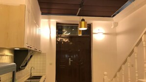 A modern kitchen with a dark wooden door, white walls, and a staircase with white balusters. - Shanghai Moxi Inn Huaihai Rd No.3 Branch (Shanghai)