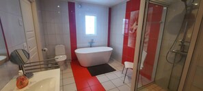 Ein modernes Badezimmer mit einer freistehenden Badewanne, einer Duschkabine aus Glas und einem WC.