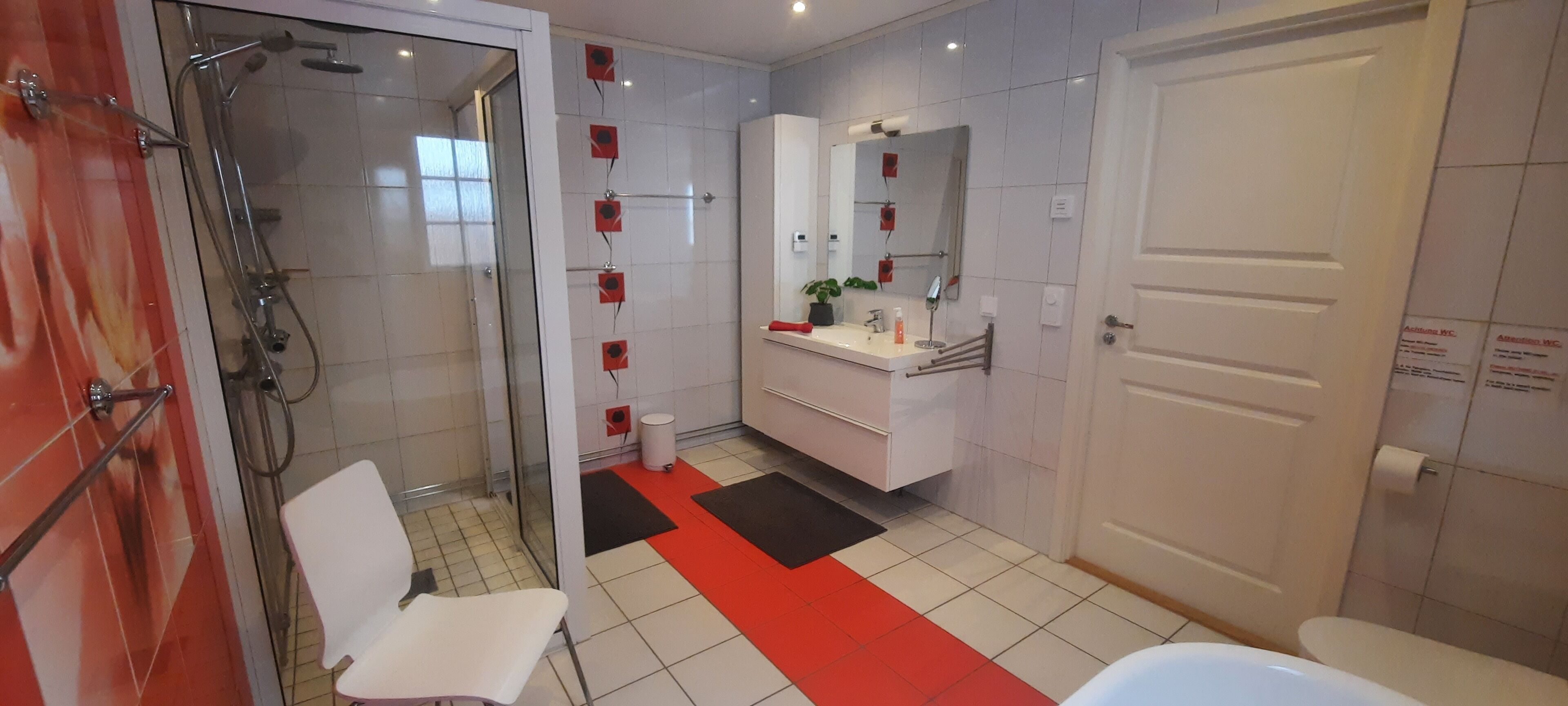 A modern bathroom with a glass shower enclosure, a white sink with a mirror, and a toilet.