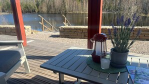 Eine Holzterrasse mit Tisch und Stühlen, einer Laterne, einem Blumentopf und einer Zeitschrift.