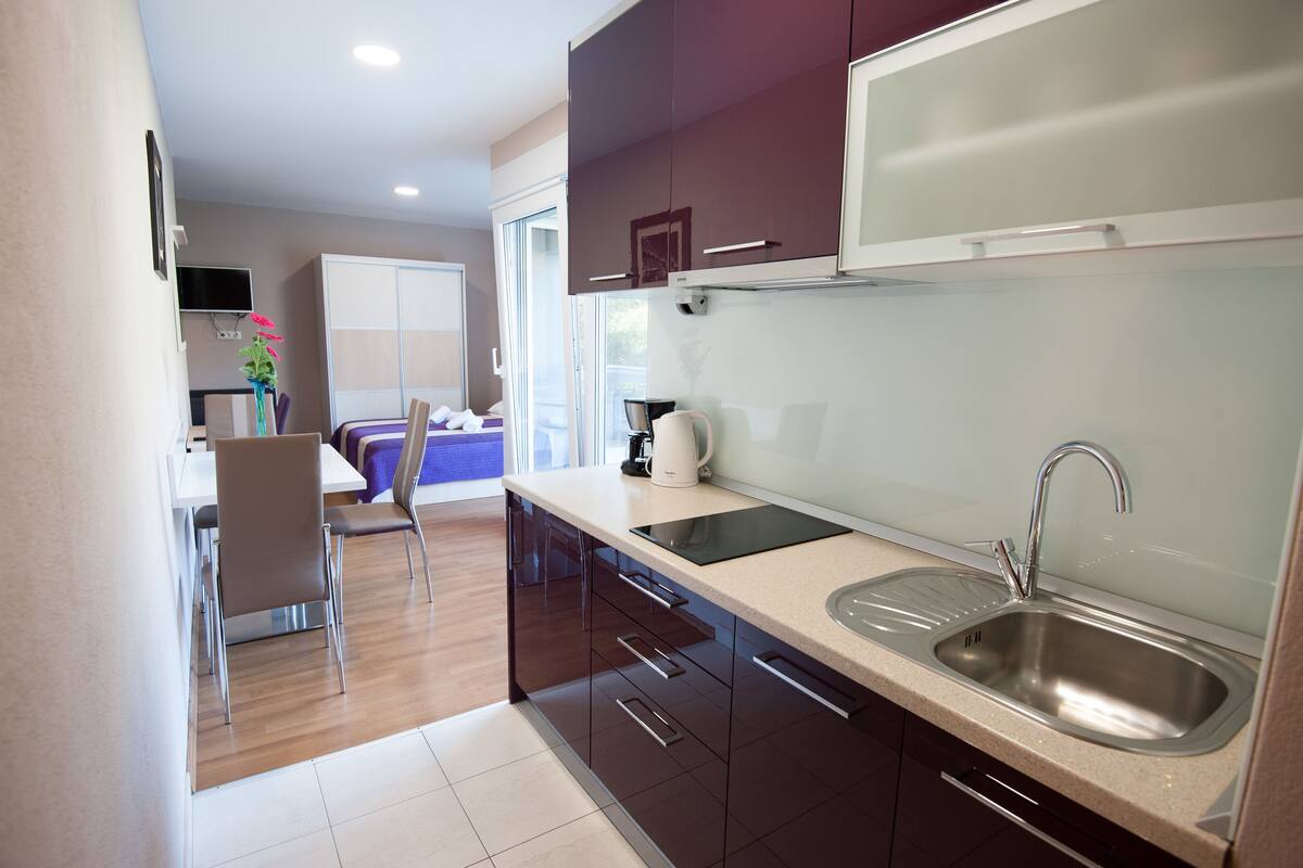 A modern kitchen with a built-in dishwasher, a sink, and a coffee maker.