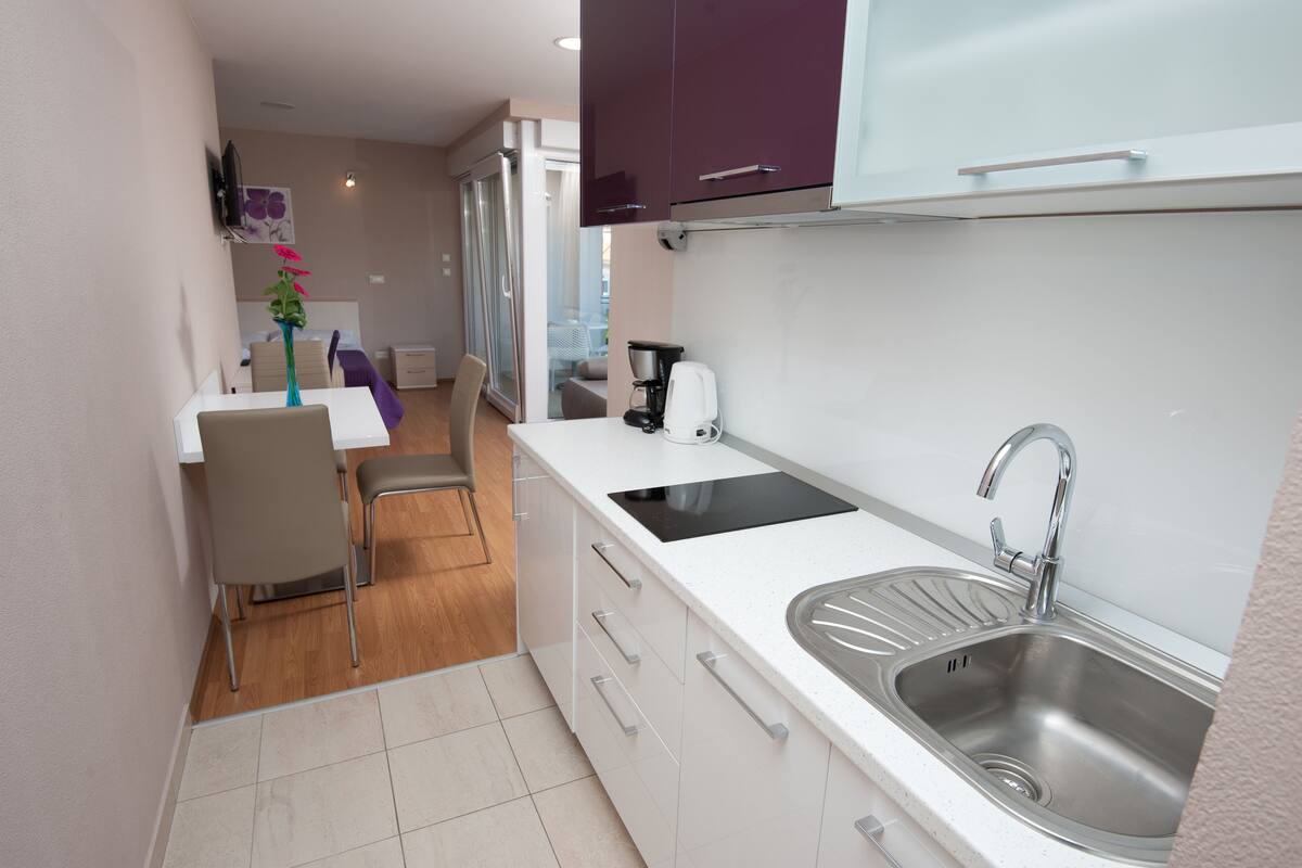 A compact kitchen with a sink, stove, and dining area.