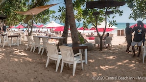 An outdoor seating area with tables and chairs, a bar, and umbrellas.