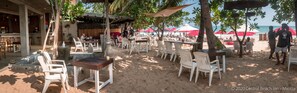 An outdoor seating area with tables and chairs, a bar, and umbrellas.