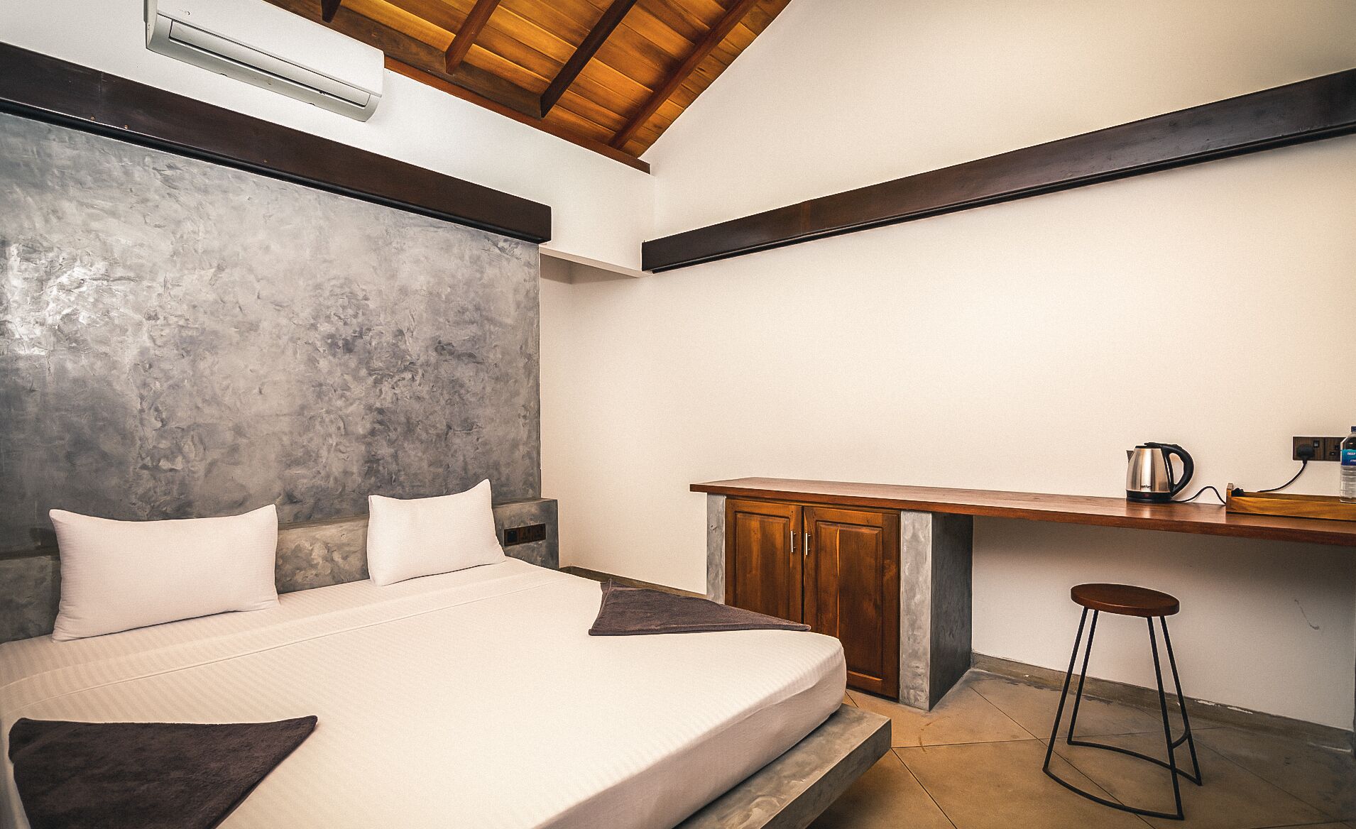 Un dormitorio con cama, una kitchenette pequeña y techo de madera.